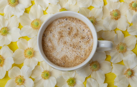 Morning white cup of coffee with foam and white anemone flowers on the table flat style.の写真素材