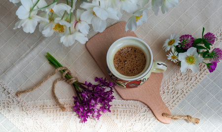 Coffee with foam and spring wildflowers on a white tablecloth.の写真素材