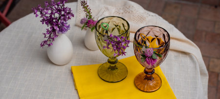 Glasses with a drink and flowers and flowers in a vase on a table with a white tablecloth.の写真素材