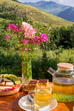 Breakfast with herbal tea on the terrace of a village house overlooking the garden and the mountains.の写真素材