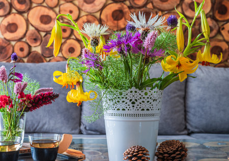A bouquet of field yellow lilies and lilac, white cornflowers in a white pot on a table in the roomの写真素材