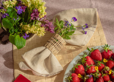 Spring forest flowers, strawberries and napkin on the tableの写真素材