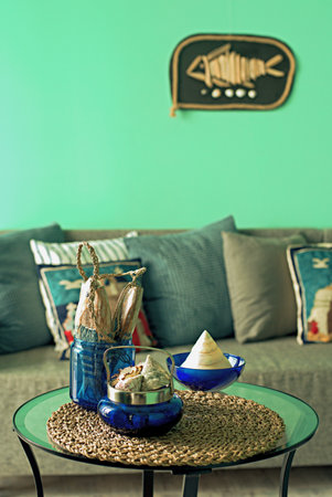 Marine style in the apartment interior - a sofa with pillows and a table with shells and fish...