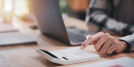 accountant using a calculator to calculate numbers ,profit and loss statement review of company performance ,cost analysis ,financial paperwork ,business account checking ,Annual budget planningの写真素材