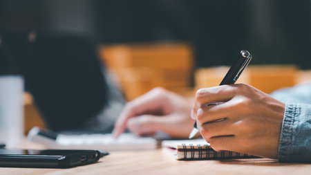 entrepreneur using a calculator to calculate numbers ,profit and loss statement review of company performance ,cost analysis ,financial paperwork ,business account checking ,Annual budget planningの写真素材