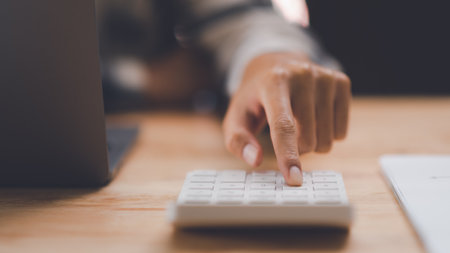 Businessman calculating figures in company financial documents with a calculator,analysis of company...