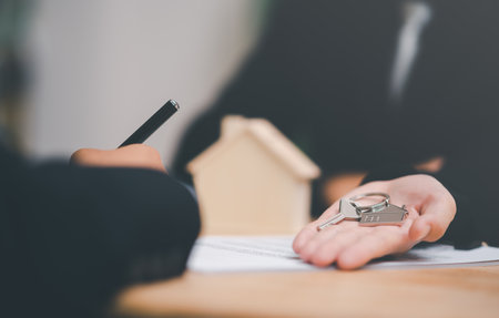 House key in the hand of a real estate agent, handle business documents and agreements, Business contract signing, commercial signing, Signing an agreement ,real estate purchase agreementの写真素材