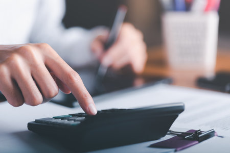 Businessman calculating figures in company financial documents with a calculator,analysis of company financial data,Planning to assess and review budgets,concept of finance and investmentの写真素材