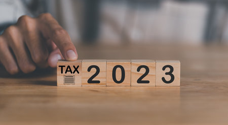 Human finger pointing at a wooden block,income tax management concepts and investment finance,...