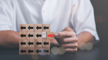 Young businessman selecting wooden blocks with red arrows and different directions Leadership concept and growth of business competition Changing Strategic Vision for Chances of Successの写真素材