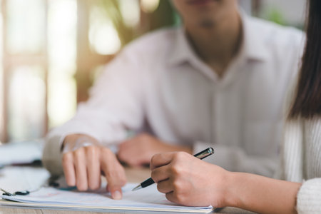 Broker pointing at documents for clients to sign, handling business documents and agreements business contract signing Approval of contract or warranty documentsの写真素材