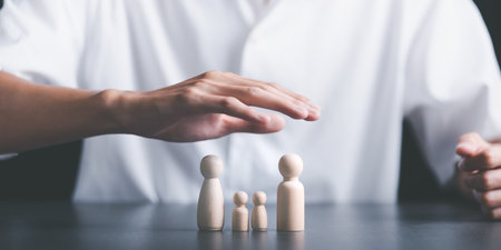 Wooden dolls and men's hands, representing protection and protection, The concept of insurance management planning,for both health and financial safety Decreasing property and family risksの写真素材