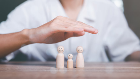 Man's hand on a wooden doll Refers to the protection and protection of safety ,concept of insurance management planning To ensure both health and financial safety,Property and Family Risk Reductionの写真素材