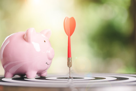 dart arrow hitting in target center of dartboard,and piggy bank, savings goals and growth-oriented...