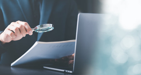 Businessman Audit documents with a magnifying glass, Quality Assessment Management with checklists, business document evaluation processes, market data report analysis and consultingの写真素材