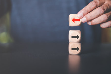 Young businessman selecting wooden blocks with red arrows and different directions Leadership concept and growth of business competition Changing Strategic Vision for Chances of Successの写真素材