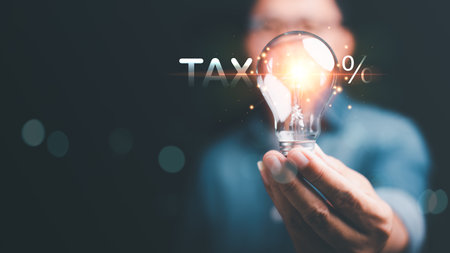 Businessman holding a light bulb ,Effective tax deduction planning ideas for individuals and companies ,Calculating business tax rates and financial budgets , Correct tax rate reductionの写真素材