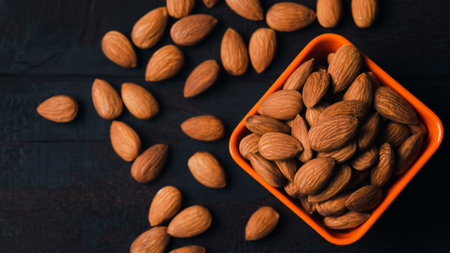 Almonds in an orange cup and placed on an old wooden table, close-up, healthy and natural eating concept without any chemical contamination.の写真素材