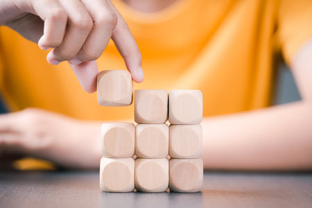 wooden block in hand of a woman in a yellow shirt arranged in an orderly mannerの写真素材