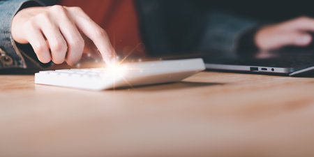 Businessman using a calculator to calculate numbers ,profit and loss statement review of company performance ,Cost analysis and calculation of financial documents ,business account checkingの写真素材