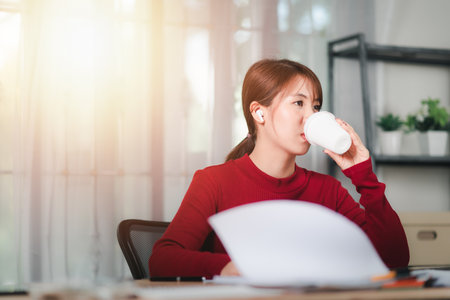 Young businesswoman enjoying and drinking hot coffee ,break during the day ,looking for creativity ,coffee break ,relaxation ,office in the morningの写真素材