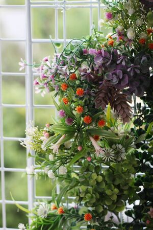 colorful plastic flowers on white wire mesh panelの写真素材