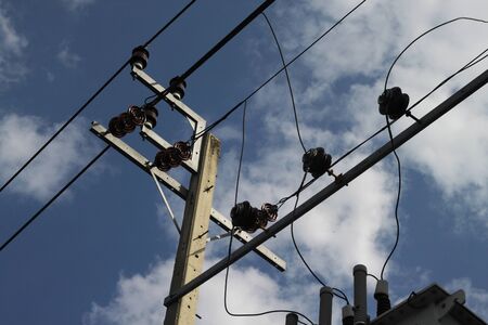electrical pole top with wires on blue sky background