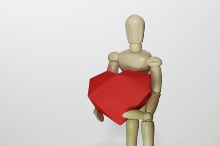 wooden manikin holding heart, isolatedの写真素材