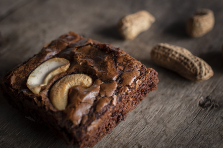 Brownie with topping Cashew Nut and peanuts put on back side. They are putting on a wooden desk.