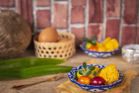 Thai desserts on a plate of white and blue stripes placed on golden cloth and wood table there are...