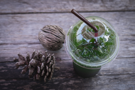 Iced green tea honey lemon drink with dried pine cones on wooden table backgroundの写真素材