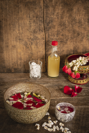 Red rose, Jasmine and popped rice on the calm water surface placed on the wood table Ready for pour water on the hands of revered elders and ask for blessing.の写真素材