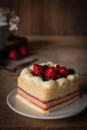 strawberry layer cake topping strawberry putting on the white plate on the wood table background.の写真素材