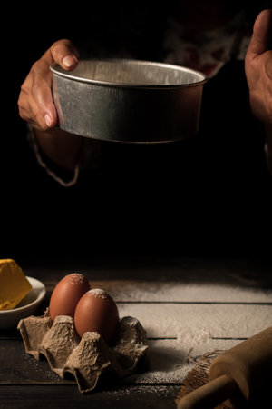 Woman sifting flour to prepare for baking. Vertical image.の写真素材