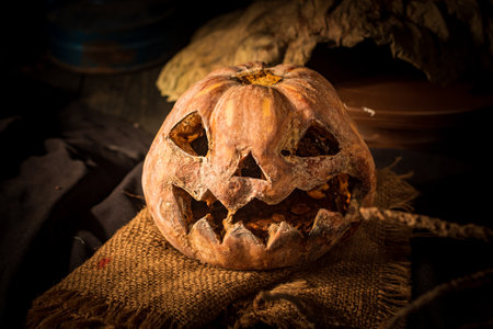 Photo of a carved Halloween jack-o-lantern pumpkin with a scary face on a wooden surface.の写真素材