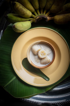 Kluay Buat Chi, a traditional Thai dessert made from ripe bananas cooked in rich coconut milk, served in a ceramic bowl with natural light still life style. Delicious Asian sweet food representing authentic Thai culture and tropical cuisine.の写真素材