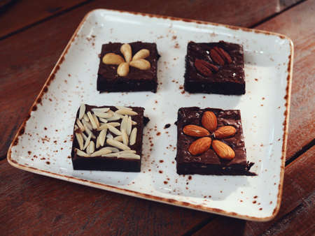 Variety of Brownies include Almond Macadamia Peanut and Chocolate Chip on the white dish and wood table from above viewの写真素材