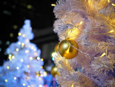 Gold ornament shiny ball on white Christmas tree. Have copy space for your text and use for blur white Christmas tree background.の写真素材