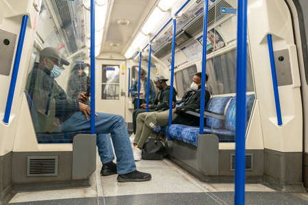 LONDON, ENGLAND - JUNE 8, 2020:  Young woman on a London Underground Tube Platform wearing a face...