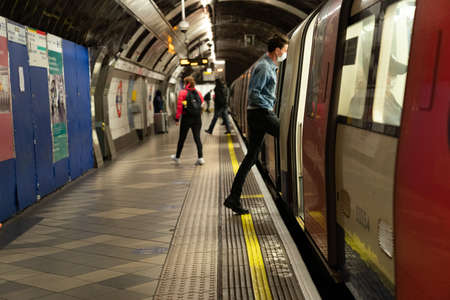 LONDON, ENGLAND - JUNE 8, 2020:  Young woman on a London Underground Tube Platform wearing a face...