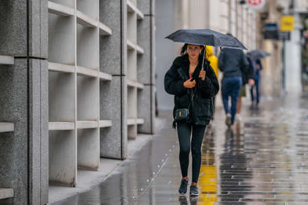 LONDON, ENGLAND - JUNE 10, 2020: Middle Aged Chinese old woman feeding the pigeons on a drizzly day in Holborn, London during the COVID-19 pandemic 065のeditorial素材