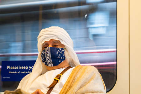 LONDON, ENGLAND - JULY 6, 2020: Elderly white haired man wearing an Arabic Keffiyeh headscarf and a face mask on the London Underground during the COVID-19 pandemicのeditorial素材