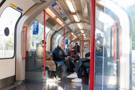 LONDON, ENGLAND - OCTOBER 23, 2020:  A group of social distancing commuting passengers travelling in a carriage on the London Underground during the COVID-19 pandemic - 025のeditorial素材
