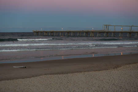 Jetty and surfboard at the beachの写真素材