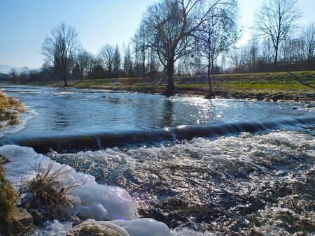 Icy Dreisam river under a bright winter sun in Freiburg, Germany