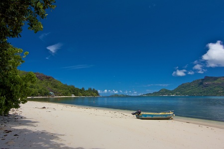 Lonely beach with a boat on a bay of Cerf island, Seychellesの写真素材