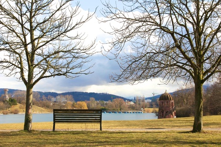 Lonely bench between naked trees on front of a lake in Freiburg, Germany