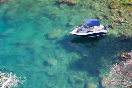 Closeup of a lonely boat in a clear bay at the Catalonian rock coast beneath the botanical garden of Palafrugell, Spainの写真素材