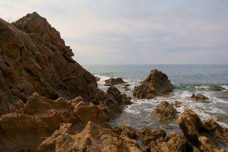 View on the Mediterranean Sea with harsh rocks in the foreground