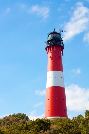 Small lighthouse against a clear blue sky with a dune full of beach grassの写真素材